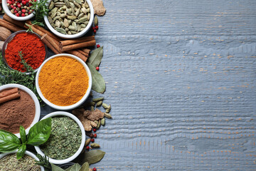 Different natural spices and herbs on grey wooden table, flat lay. Space for text