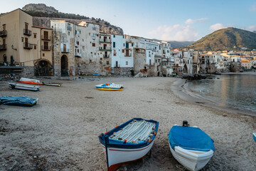 Fototapeta na wymiar Beautiful old harbor with wooden fishing boats,colorful waterfront stone houses and sandy beach in Cefalu, Sicily, Italy.Attractive summer cityscape,traveling concept background.Italian vacation.