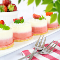Mini coconut and strawberry cheesecakes. Monoportions of summer dessert with coconut, white chocolate and fresh strawberries.