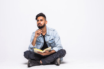 Handsome young man reading a book sitting on the floor