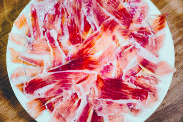 Appetizing slices Iberian ham. Acorn-fed Iberico Ham. Pata negra, spectacular vision of sliced ham. Typical spanish or catalan food. - obrazy, fototapety, plakaty