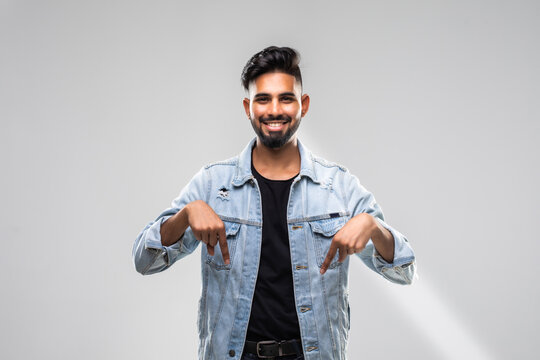 Shocked male looks down with great disbelief, expresses surprisment and astonishment, indicate with fore fingers at floor, isolated over white concrete wall.