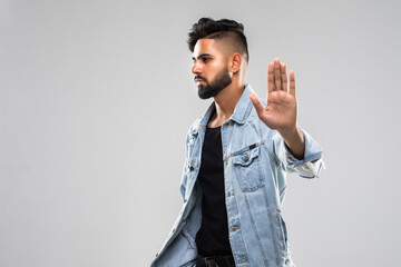 Full length portrait of man which holding arm on hip and showing stop sign at camera. Isolated white background