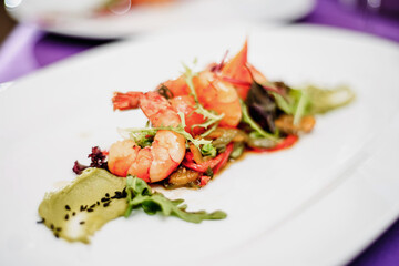 Classic salad with grilled tiger prawns, lettuce, vegetables and sauce on a white plate on a table in a restaurant. Room service breakfast. Close-up macro. Space