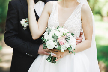 Beautiful young wedding couple posing with bouquet of flowers in hands