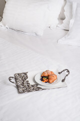 Fototapeta na wymiar Breakfast in bed. Croissants with fresh berries on white plate on chic silver tray on white beautiful bed. Room service. French breakfast
