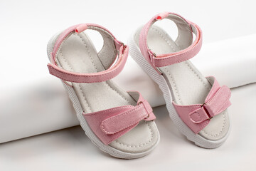 Pink children's sandals made of shiny leather with Velcro fasteners, flat white soles, isolated on a white background. A pair of fashionable children's sandals for a comfortable walk. 