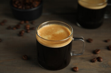 Cup of hot aromatic coffee and roasted beans on wooden table