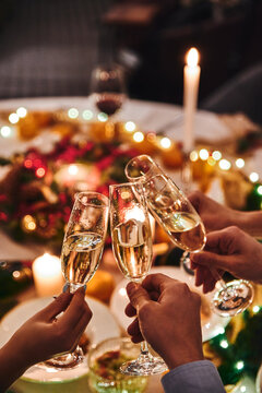 Cheers with champagne. People clink glasses of champagne at the holiday table on New Year's Eve. High quality photo