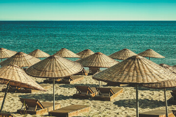 an empty beach in retro style with  beach umbrellas, sun loungers and a clear sky
