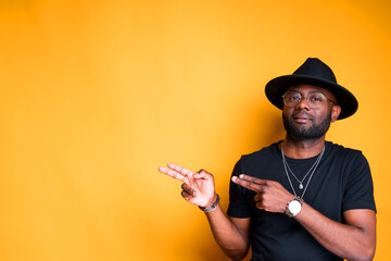 Stylish attractive african american man in a hat shows with interest to the side