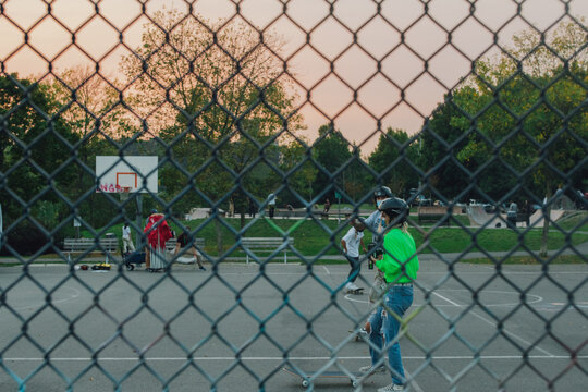 pandemic skateboard girl behind chainlink fence in public park