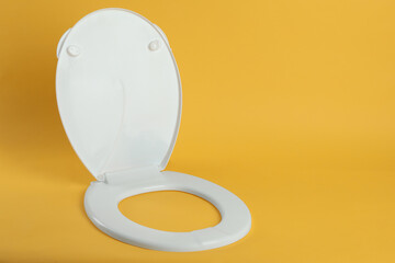 New white plastic toilet seat on yellow background, space for text