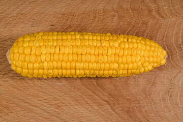 Ripe corn in a roach, peeled from husk, on a wooden board