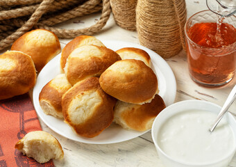 Cottage cheese pastry pies, vatrushka in Russian cuisine Pitcher and glass of compote bowl of sour cream or yogurt on wooden background