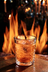 conceptual Negroni cocktail with glitter in a beautiful glass on copper designer bar counter, the background of real fire. Series of photo. High quality photo