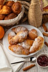 cottage cheese bagels in powdered sugar lie on a white plate with jam on a wooden background