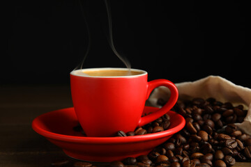 Cup of tasty coffee and beans on wooden table