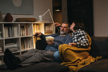 couple relaxing at home watching tv while sitting on a sofa.