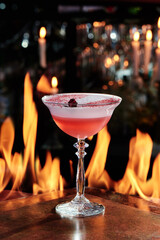 pink cocktail with white foam top in a beautiful glass on copper designer bar counter, the background of real fire. Series of photo. High quality photo