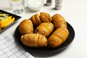 Delicious homemade Hasselback potatoes served on white wooden table