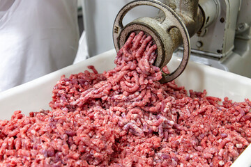 Meat being ground in a meat grinder. In a restaurant