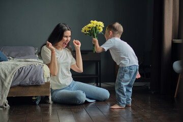 Naklejka premium Happy mother day. child son congratulates mother on holiday and gives flowers. congratulating her on mother's day during holiday celebration at home
