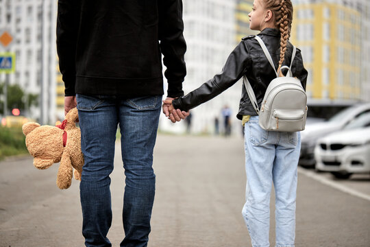 Maniac man holds the hand of teenage girl in street. The concept of kidnapping and child trafficking. View from back on pedophile and caucasian child girl walking along the street. Crime, violence