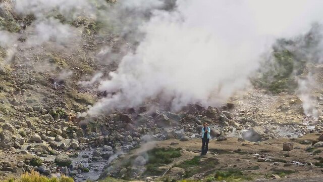 Hiking and eco tourism female person shoots video at geyser