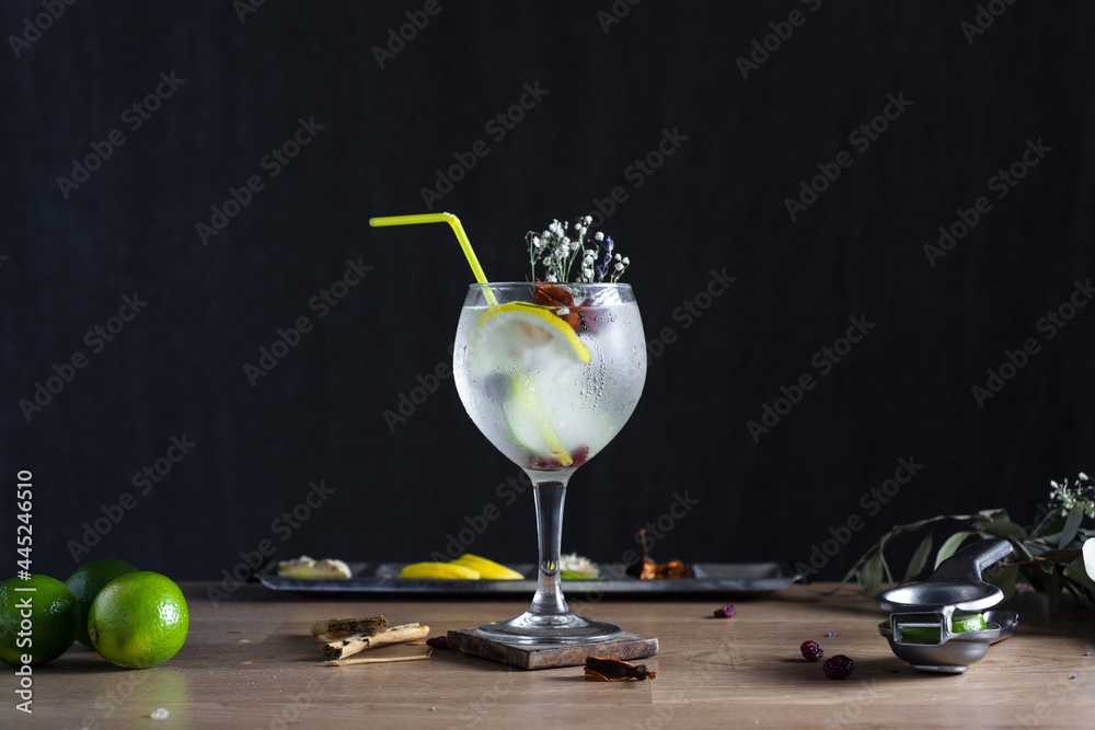 Sticker Freshly prepared gin and tonic with a plastic straw on a wooden table