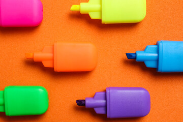 Set of highlighters on orange background, flat lay