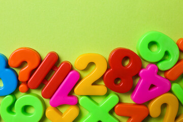 Obraz premium Colorful magnetic numbers on light green background, flat lay