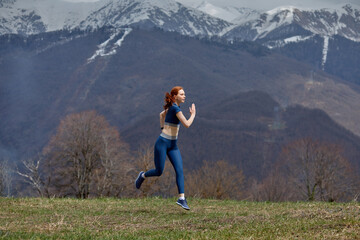 Obraz premium Running woman. Red-haired Female Runner Jogging during Outdoor Workout in nature in mountains. Beautiful fit woman in sportswear. Fitness model outdoors. Weight Loss. Healthy lifestyle. Morning