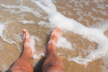 Tanned bare men's feet on  a sea coast