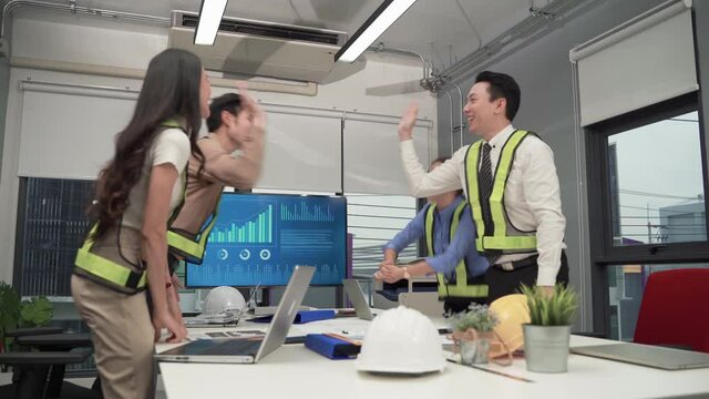 At the meeting of the engineering team, they performed high five rejoicing after achieving their goals in their work.
