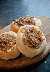 Tasty onion roll on wooden plate