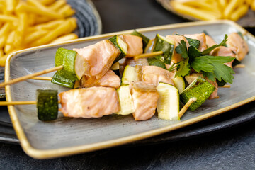 Salmon and zucchini kebabs on skewers on a gray plate
