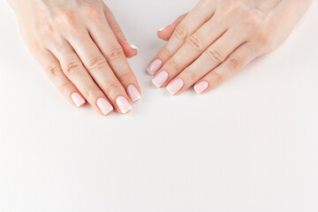 Female hands with beautiful stylish french manicure above white background with copy space