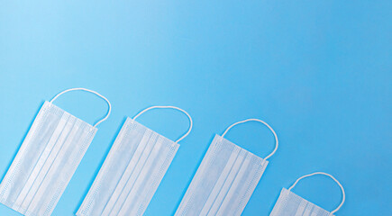 Medical banner with line of face masks shooted above blue background with copy space. Close up, cropped image, top view.