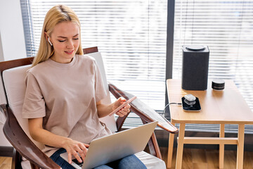 Adult female work on laptop in room, using Wireless bluetooth speaker and other devices. Column...