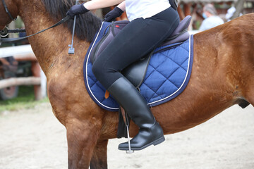 Old leather saddle with stirrups for show jumping race. Equestrian sport event background