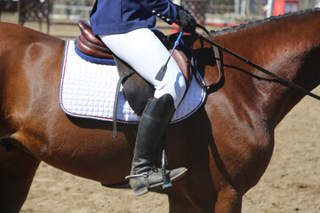 Old leather saddle with stirrups for show jumping race. Equestrian sport event background