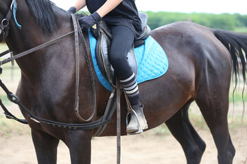 Old leather saddle with stirrups for show jumping race. Equestrian sport event background