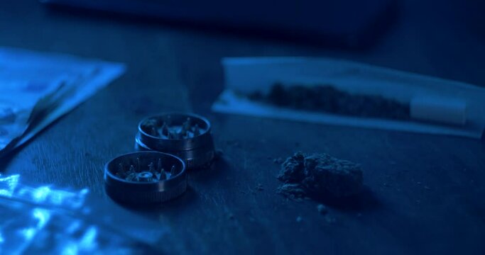 Man rolling a medical marijuana joint in night club. Close up of addict marijuana joint with lighter. Drugs narcotic concept. Close up . Drug use. Man preparing and rolling marijuana cannabis joint.