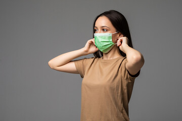 Portrait of a young woman in a medical mask isolated over grey background. Young girl patient...