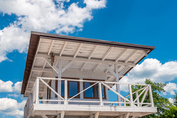 White lifeguard booth against blue, cloudy sky