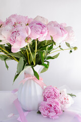 Bouquet of peonies in a white vase on a white background.