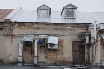 The roof of an old house against the sky with ventilation pipes and attics. Chimneys on a metal roof