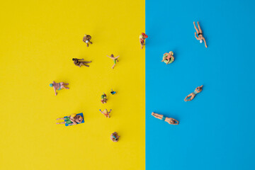 Miniature people: yellow and blue paper as symbol for beach and the sea with swimming or sunbathing...