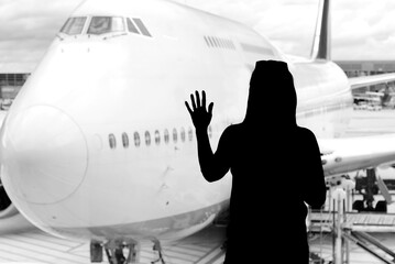 Black woman silhouette looking to aircraft in the airport hall- missed or cancelled flight concept....